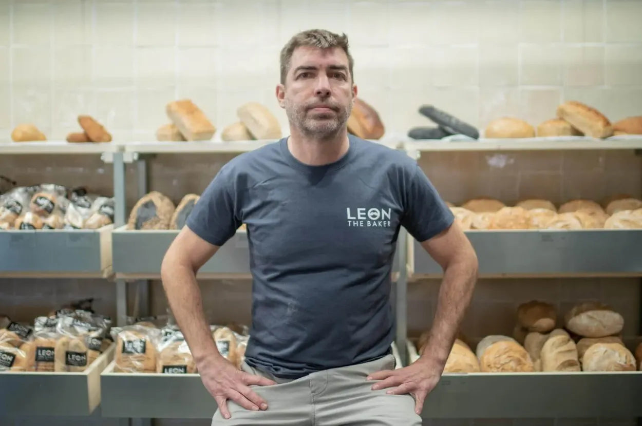 Persona en una panadería rodeada de diferentes tipos de pan